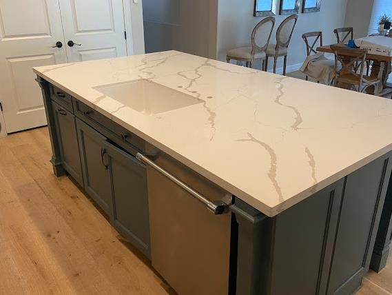 Calacatta quartz island with sage cabinets by Mauricio's StoneCraft
